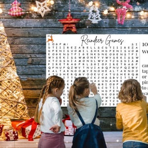 May include: A Christmas-themed scene with a word search puzzle labeled "Reindeer Games" and the text "100 words can be taped or pinned to a wall!" Three children are looking at the puzzle. Decorative lights and ornaments are in the background.
