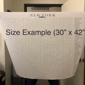 May include: A black and white word search puzzle poster featuring the word "NEW YORK" at the top. The poster is being held by a person's hands and shows a size example of 30 inches by 42 inches. The poster includes a list of words related to New York City.