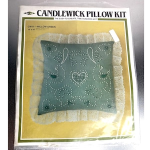 Op de afbeelding: Een kussenkit met een groen, geborduurd kussen met een hart- en bloemmotief. Het kussen is 35,5 x 35,5 cm en heeft een crèmekleurige kanten rand. De verpakking leest "CANDLEWICK PILLOW KIT" en "WILLOW GREEN".