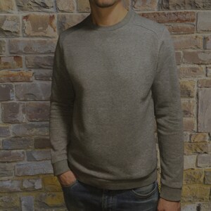 May include: A gray long-sleeved sweatshirt with a crew neck.