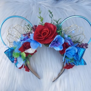 May include: A blue and gold headband with red and blue flowers, seashells, and a blue bow.