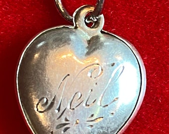 Antique Sterling Silver heart charm with an amethyst color stone and the name “Neil”