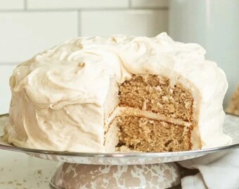 May include: A two-tier cake frosted with a thick layer of white buttercream frosting. One slice is missing, revealing the cake layers.