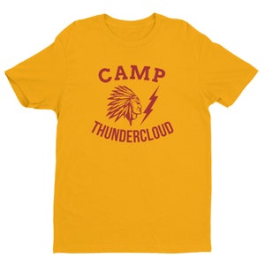 May include: A yellow short-sleeved t-shirt with a red graphic design. The graphic features a Native American headdress with a lightning bolt and the text "CAMP THUNDERCLOUD".