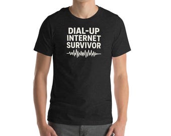 May include: A dark grey t-shirt featuring the white text "DIAL-UP INTERNET SURVIVOR" above a white heartbeat graphic. The t-shirt is short-sleeved and worn by a person.
