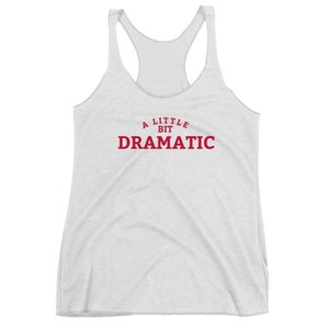 May include: A light gray racerback tank top with the text "A Little Bit Dramatic" in red letters. The tank top has a scoop neck and a racerback design.