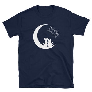 May include: Navy blue t-shirt with a white crescent moon and two cats sitting back to back. The text "Hand in Hand is the only way to lead" is printed on the shirt.
