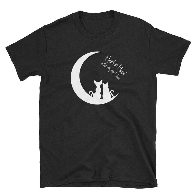 May include: Black t-shirt with a white crescent moon and two cats sitting back to back. The text "Hand in Hand is the only way to lead" is written inside the moon.