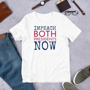 May include: White t-shirt with the text "IMPEACH BOTH PRESIDENTS NOW" in blue and red lettering.