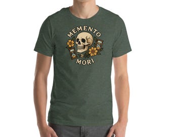 May include: Green t-shirt featuring a skull graphic with the words "Memento Mori". The design includes yellow flowers and hourglasses. The shirt is made of a soft material.