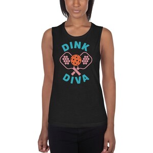 May include: Black sleeveless shirt with the words "Dink Diva" in turquoise and a pink and orange pickleball graphic. The shirt is a casual style, suitable for sports or everyday wear.