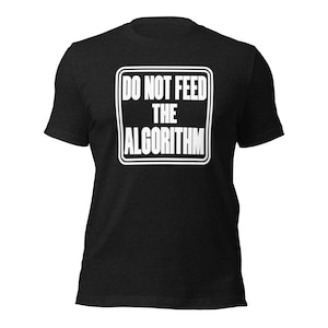 May include: A black short-sleeved t-shirt featuring a white rectangular graphic on the chest. The graphic is a white-bordered square containing the bold white text DO NOT FEED THE ALGORITHM in a sans-serif font, centered on the front of the shirt.