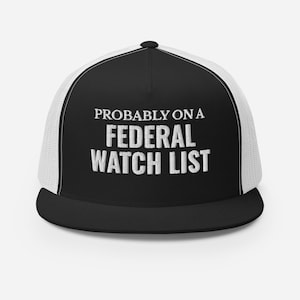 May include: Black and white trucker hat with a white mesh back. The hat has the text "PROBABLY ON A FEDERAL WATCH LIST" embroidered on the front in white.