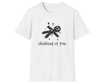 May include: White t-shirt with a black graphic of a voodoo doll with pins and the text "thinking of you".