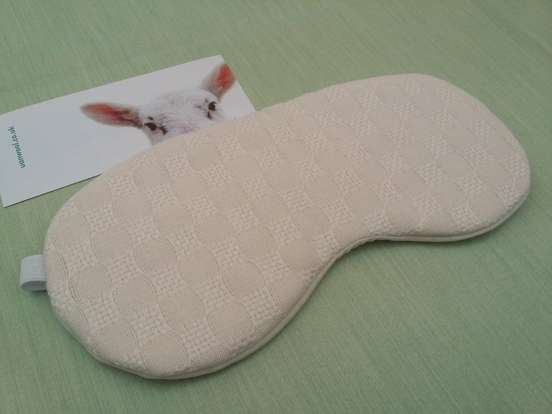 Sleeping eye mask . soft Ivory cream  coloured silk & wool fabric with gentle hatch pattern  on outer side and plain cream wool challis material on side next to eyes. White elastic strap hand made by Uan Wool, Angus, Scotland