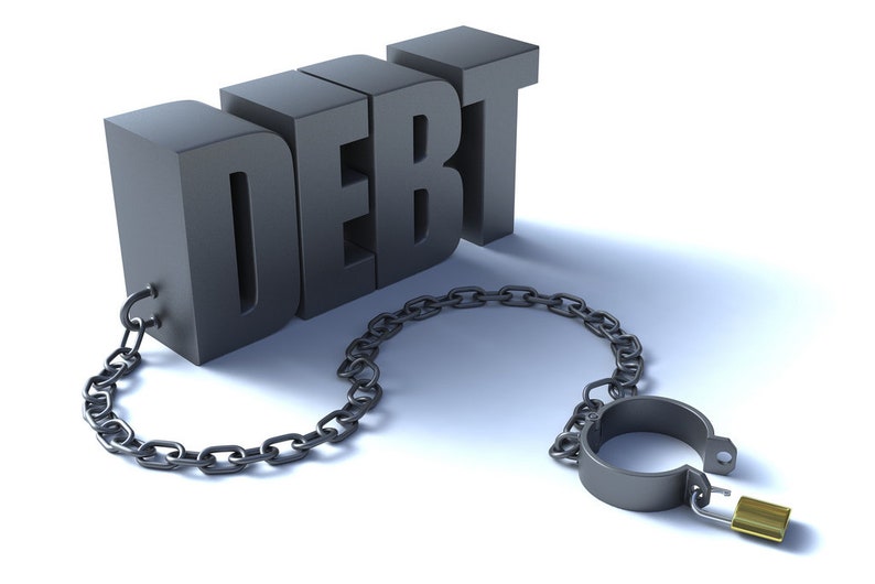 May include: The word "DEBT" is made of metal and is attached to a metal chain and padlock. The chain is looped around the word "DEBT".