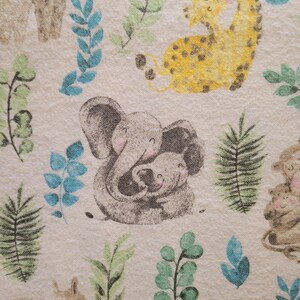 May include: A beige fabric with a repeating pattern of animals and leaves. The animals include a giraffe, an elephant, and a bear. The leaves are green and blue.