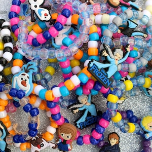 Könnte beinhalten: Ein Haufen bunter Perlenarmbänder mit Frozen-Charakteranhängern. Die Anhänger zeigen Elsa, Anna, Olaf und Kristoff. Die Armbänder sind aus verschiedenen Perlenfarben gefertigt, darunter Blau, Gelb, Orange, Pink und Weiß.