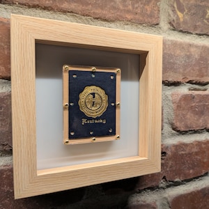 Könnte beinhalten: Ein gerahmter Druck eines blauen und goldenen Siegels der University of Kentucky mit dem Text "Kentucky" unter dem Siegel.