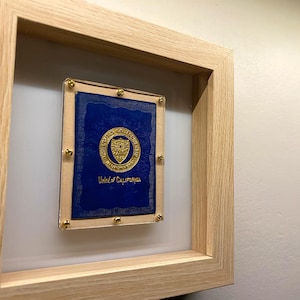 May include: A framed certificate with a gold seal and the text "University of California" on a blue background.