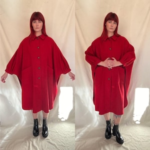 May include: A red wool coat with a button-up front and large pockets. The coat has long sleeves with a gathered detail at the elbow. The model is wearing black ankle boots.