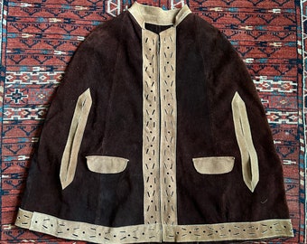 May include: A brown suede cape with a zipper closure and tan suede trim. The cape has a stand-up collar and two pockets.