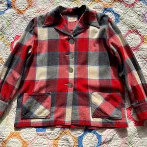 May include: A vintage jacket in a red, grey, and cream plaid pattern. It features a collared neckline, button fastening, and two front pockets. The long-sleeved jacket has a classic, tailored fit, ideal for a retro style.