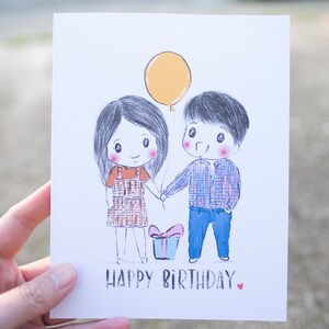 Puede incluir: Una tarjeta de cumplea&ntilde;os con una ilustraci&oacute;n dibujada a mano de dos personas que se toman de la mano. La tarjeta tiene un globo amarillo, una caja de regalo con un lazo rojo y el texto "Feliz cumplea&ntilde;os".