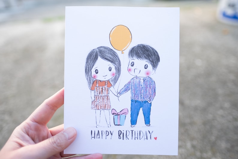Puede incluir: Una tarjeta de cumplea&ntilde;os con una ilustraci&oacute;n dibujada a mano de dos personas que se toman de la mano. La tarjeta tiene un globo amarillo, una caja de regalo con un lazo rojo y el texto "Feliz cumplea&ntilde;os".