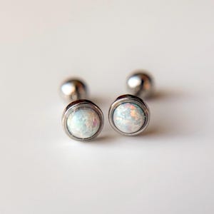 May include: A pair of silver stud earrings with white opal stones.