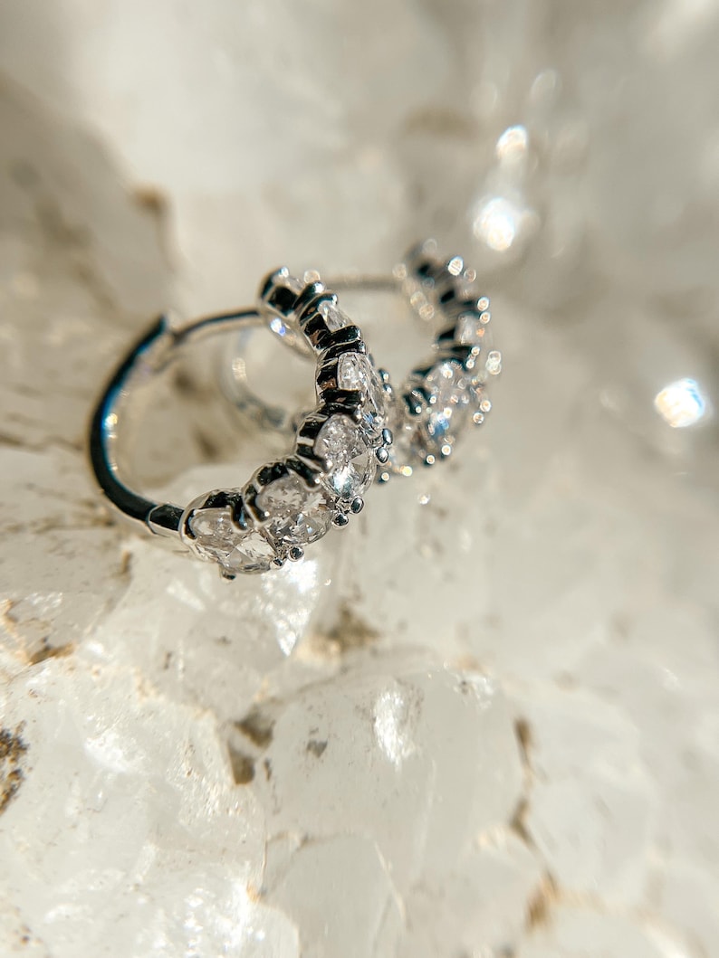 May include: Silver hoop earrings with a row of clear cubic zirconia stones.