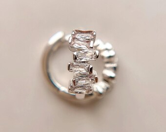 May include: Silver hoop earring with a row of clear baguette-shaped cubic zirconia stones.