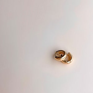 May include: A pair of gold hoop earrings. The hoops are thick and have a smooth, polished finish.