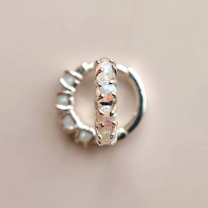 May include: A pair of silver hoop earrings with a row of white opal stones set in each hoop.