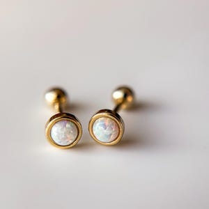 May include: A pair of gold stud earrings with white opal stones.
