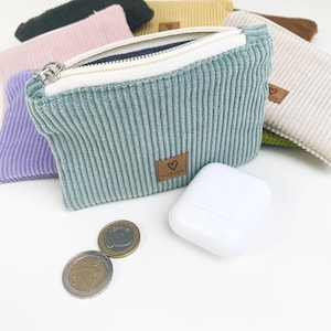 May include: A set of six small zippered pouches in various colors, including green, pink, beige, and brown. The pouches are made of a soft, textured fabric and have a small heart-shaped logo on the front.