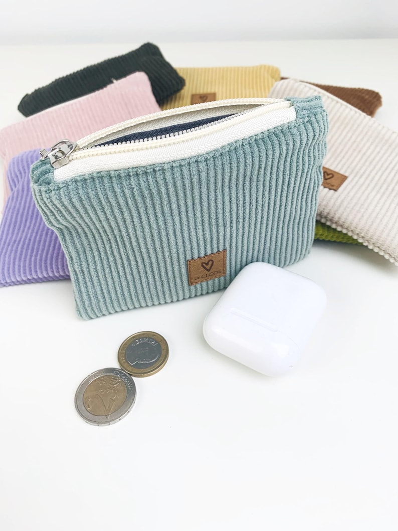 May include: A set of six small zippered pouches in various colors, including green, pink, beige, and brown. The pouches are made of a soft, textured fabric and have a small heart-shaped logo on the front.