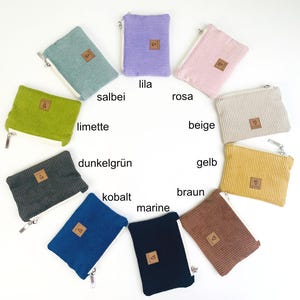 May include: Assortment of 10 small zippered pouches in various colors, including lime green, dark green, navy blue, brown, beige, yellow, pink, purple, and gray. Each pouch has a small brown leather tag with a heart symbol.