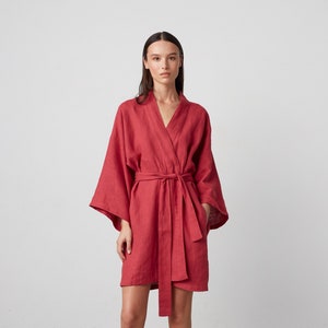 May include: A red linen robe with a wrap style and a tie belt. The robe has long sleeves and a relaxed fit.