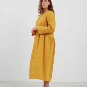 May include: A long-sleeved, mustard yellow linen dress with a gathered skirt and a round neckline.