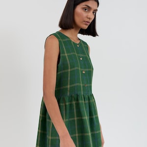 Front three-quarter view of the FERN Green Check linen midi dress with hand in side seam pocket showing the sleeveless cut and gathered skirt