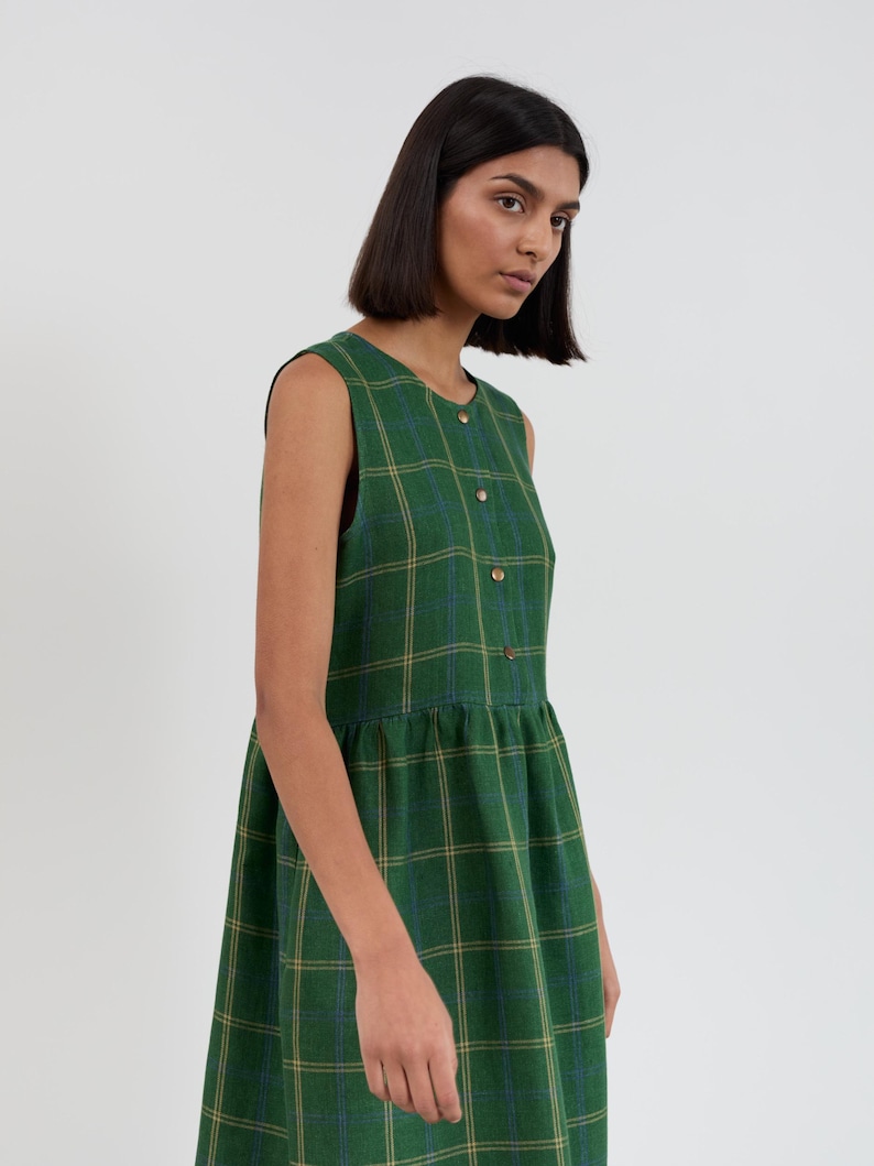 Front three-quarter view of the FERN Green Check linen midi dress with hand in side seam pocket showing the sleeveless cut and gathered skirt