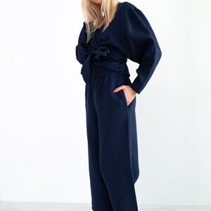 May include: A navy blue linen wrap top with long sleeves and a tie at the waist, paired with matching wide-leg pants.
