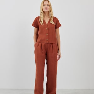 May include: A rust-colored linen top with a v-neck and short sleeves, paired with matching wide-leg linen pants. The top has a button-up front.