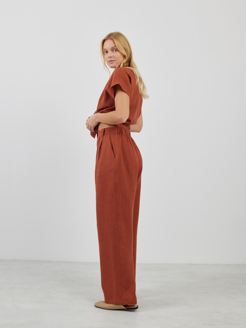 May include: A rust-colored linen top and matching wide-leg pants. The top has a short sleeve and a relaxed fit. The pants have a high waist and a straight leg.