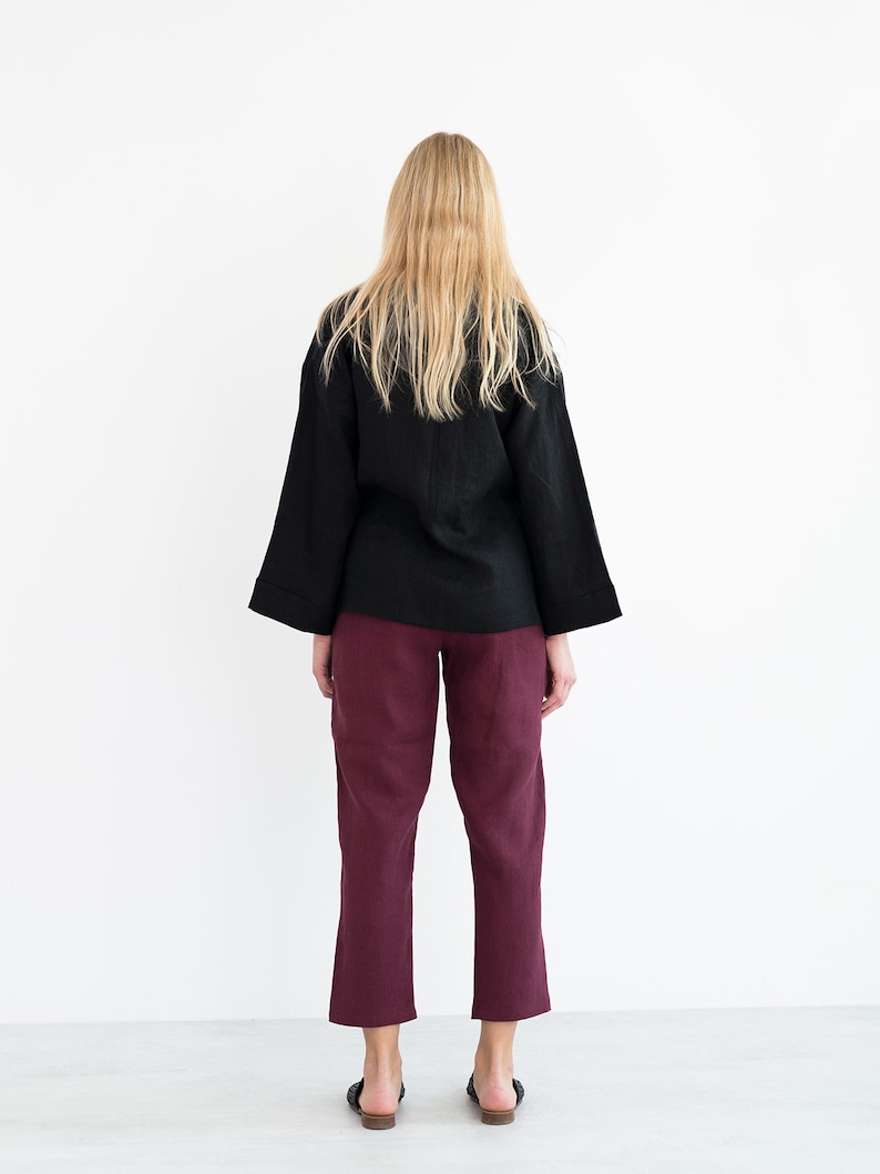 Op de afbeelding: Een zwart linnen top met lange mouwen en een bordeauxrode linnen broek.