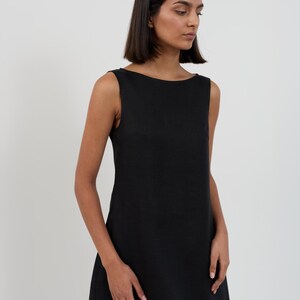 Close-up three-quarter view of the CECILIA dress in Black highlighting the wide boat neckline, sleeveless cut, and linen texture