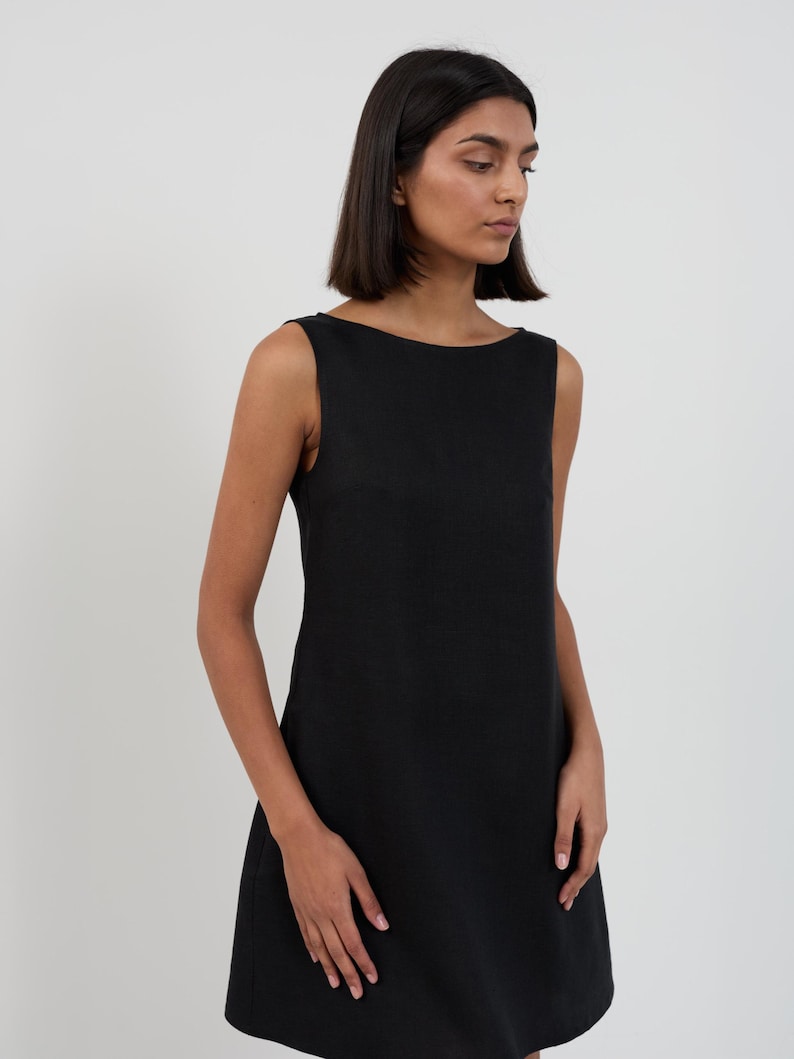 Close-up three-quarter view of the CECILIA dress in Black highlighting the wide boat neckline, sleeveless cut, and linen texture