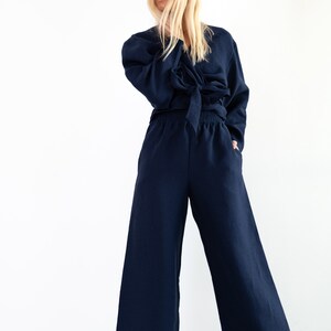 May include: A navy blue linen wrap top and wide-leg pants set. The top has a tie at the waist and long sleeves. The pants have an elastic waistband.