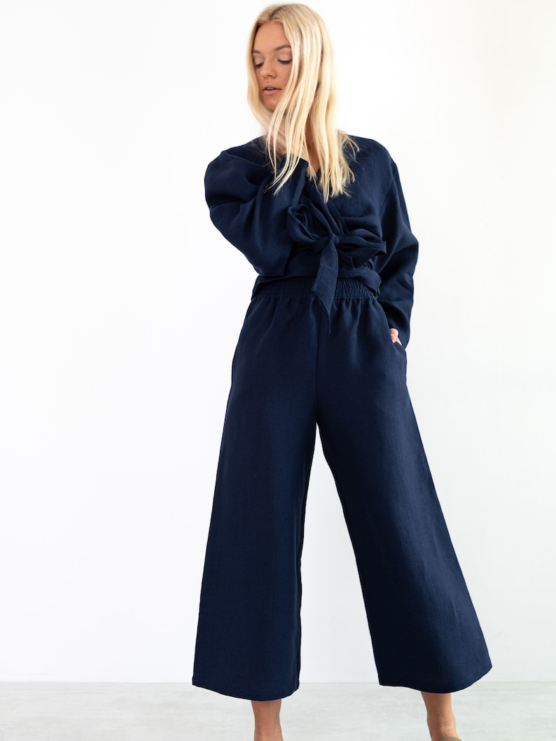 May include: A navy blue linen wrap top and wide-leg pants set. The top has a tie at the waist and long sleeves. The pants have an elastic waistband.